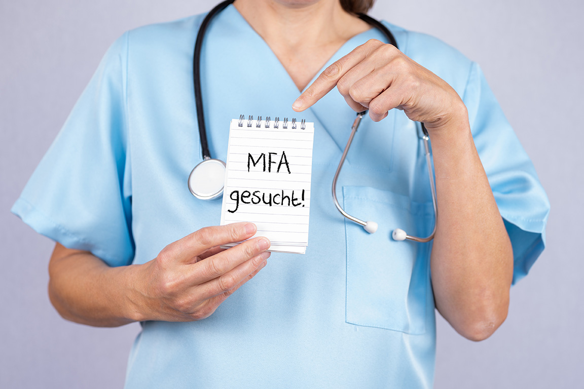Arzthelferin zeigt auf einen Notizblock auf dem MFA gesucht ste